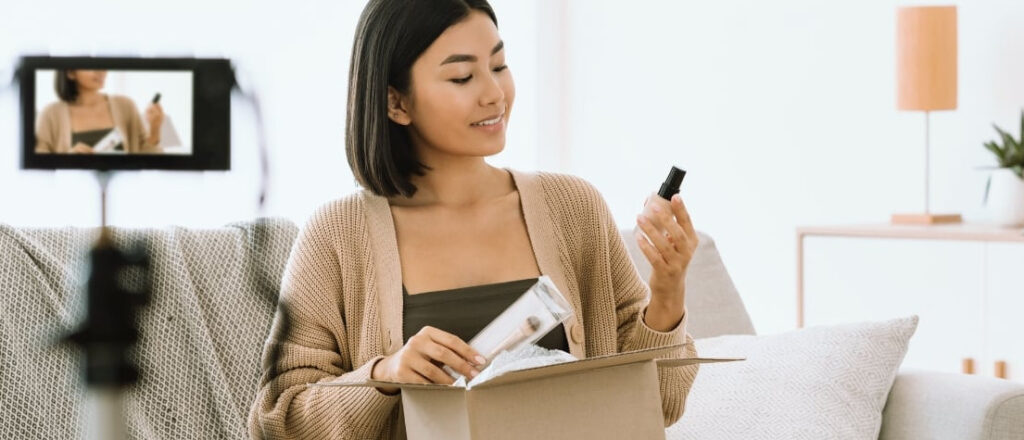 Une femme assise sur un canapé, tenant un téléphone portable dans ses mains.