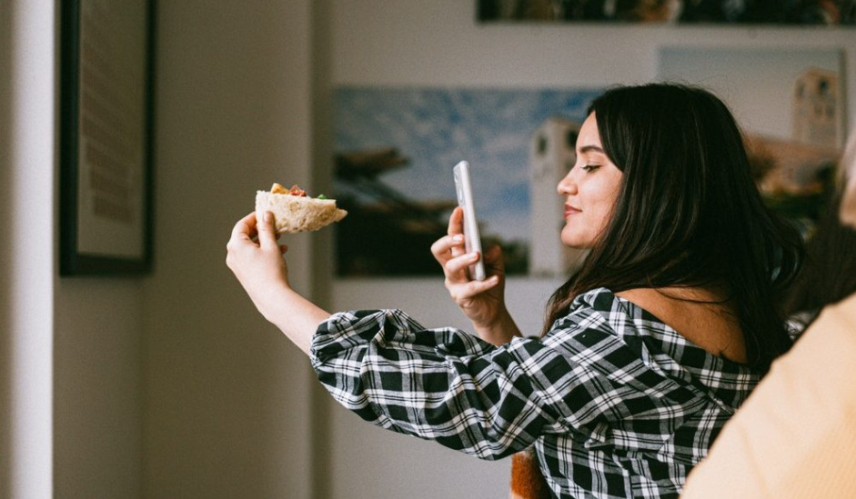 Instagram influencers: Une femme prenant une photo de son plat savoureux dans un restaurant, capturant un moment de plaisir culinaire.